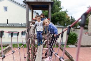 Zwei Kinder laufen über die Wackelbrücke des Spielhauses