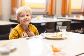 Ein Junge sitzt beim Essen und lächelt in die Kamera
