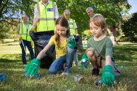 Kinder und Erwachsene sammeln Müll auf